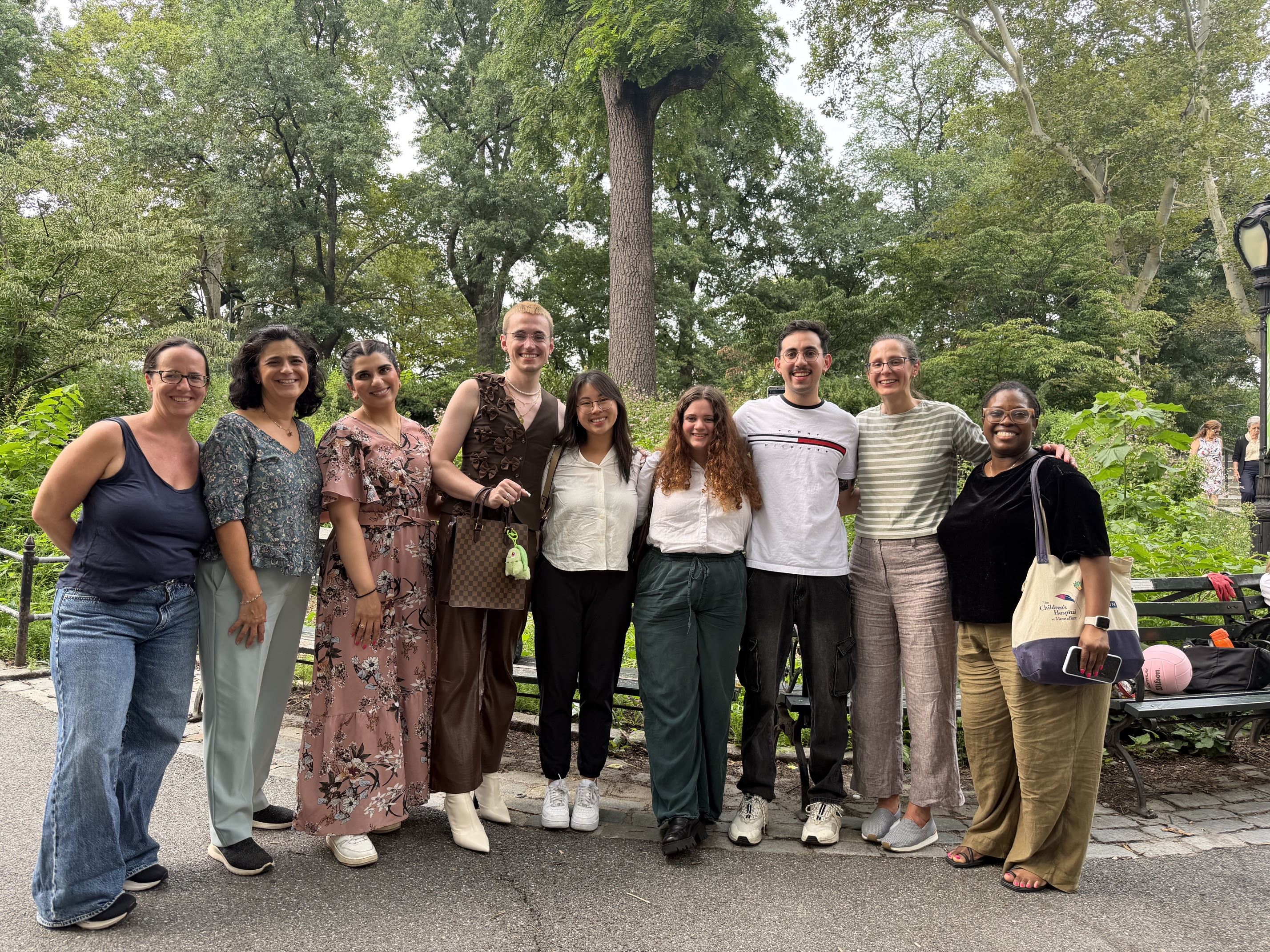 Diverse group of smiling healthcare professionals sitting together on a sunny outdoor patio during a social break.